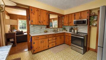 Una cucina con mobili in legno, un frigorifero in acciaio inossidabile e un forno a microonde.