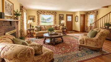 A traditional living room with a fireplace, floral-patterned furniture, and a large rug.