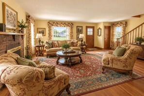 A traditional living room with a fireplace, floral-patterned furniture, and a large rug.