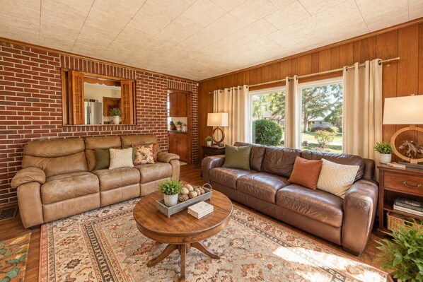 A living room with two leather sofas, a coffee table, and a brick wall.