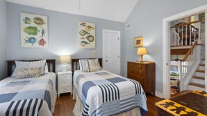 Un dormitorio con dos camas, un aparador, una lámpara y una escalera que lleva a un nivel superior.