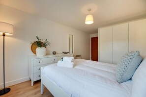 Ein Schlafzimmer mit Bett, Nachttisch, Lampe und Kleiderschrank.
