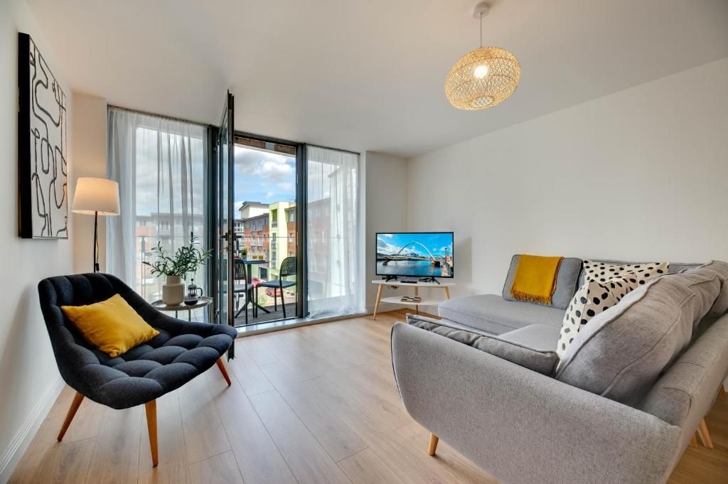 A modern living room with a sofa, a chair, a television, and a large window.
