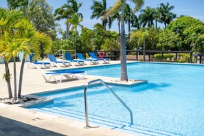 A pool area with lounge chairs and palm trees. - Richmond Retreat | Pool| Gym | Gated| Beach Access (Plantation Village)