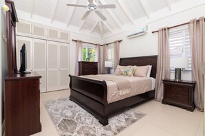 A bedroom with a bed, a dresser, a nightstand, a ceiling fan, and a window with curtains. - Richmond Retreat | Pool| Gym | Gated| Beach Access (Plantation Village)