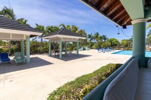 A covered outdoor area with a pool, lounge chairs, and a gazebo. - Richmond Retreat | Pool| Gym | Gated| Beach Access (Plantation Village)