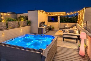 A rooftop patio with a hot tub, outdoor seating, and string lights. - 11 Beds Hot Tub Game Room Rooftop Grill (Nashville)