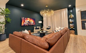 A modern living room with a large leather sofa, a fireplace, and a chandelier. - 11 Beds Hot Tub Game Room Rooftop Grill (Nashville)