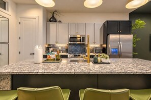 A modern kitchen with a central island, stainless steel appliances, and a dark backsplash. - 11 Beds Hot Tub Game Room Rooftop Grill (Nashville)