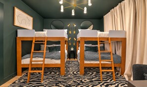 Ein Zimmer mit Etagenbetten, einem zebraartig gemusterten Teppich und einer Kristallleuchter.