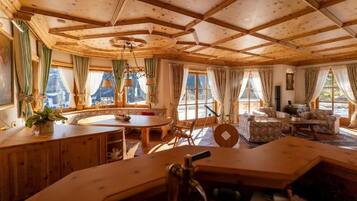 Una habitación acogedora con techo de madera, una mesa redonda para comer y un sofá.