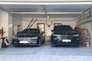 A garage with two cars parked side by side, a ski rack, and a deer head mounted on the wall.