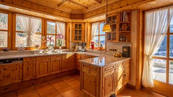 A spacious kitchen with wooden cabinets, granite countertops, and large windows offering scenic views.