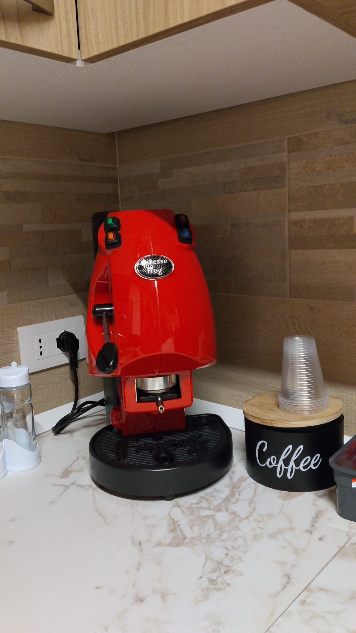 A red coffee machine on a kitchen counter with a 'Coffee' sign.