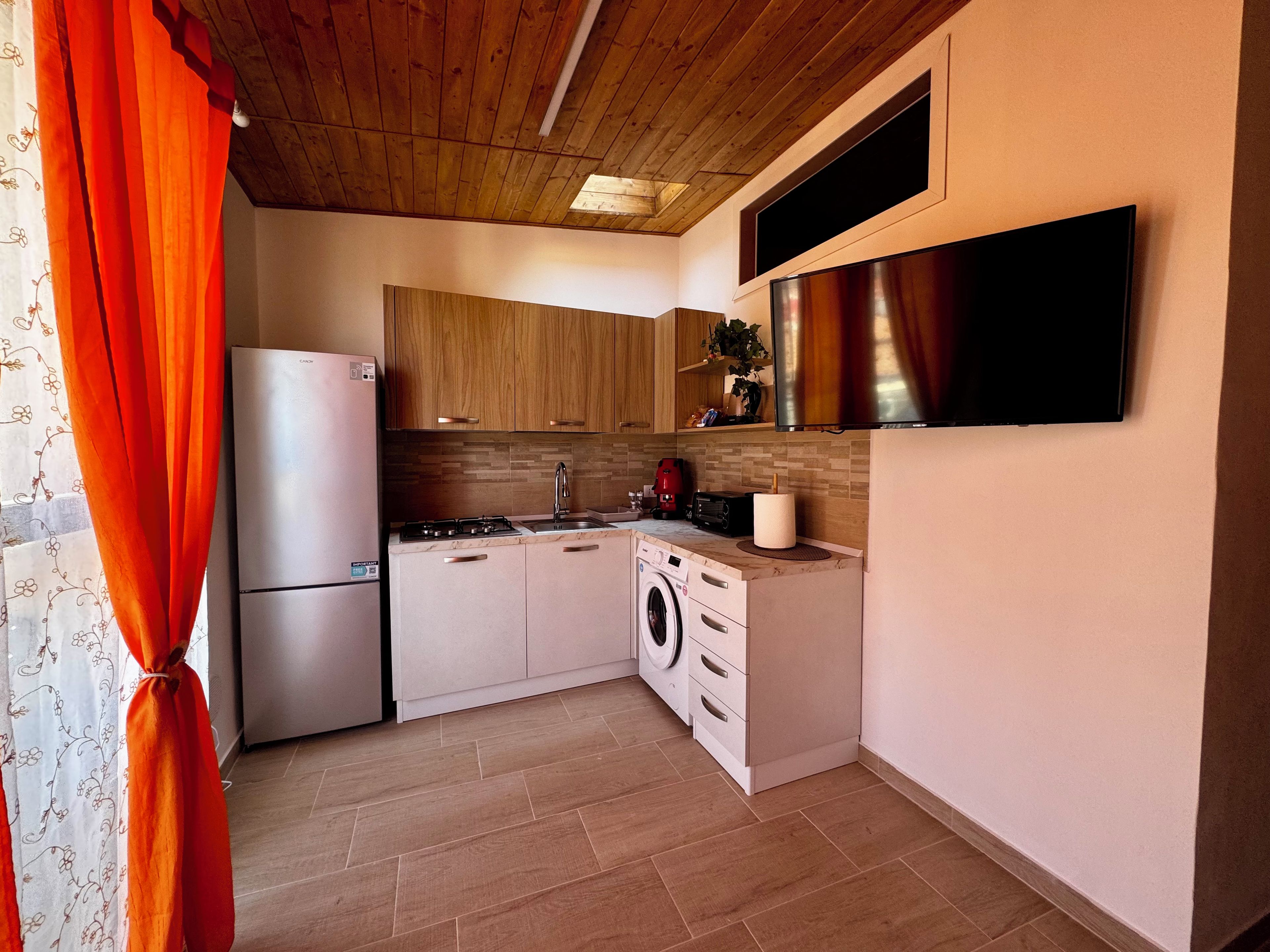 Eine kleine Küche mit Kühlschrank, Herd, Spüle und Waschmaschine.