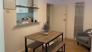 Et moderne køkken med indbygget ovn, et spisebord med bænke og en grå sofa i en opholdsstue.