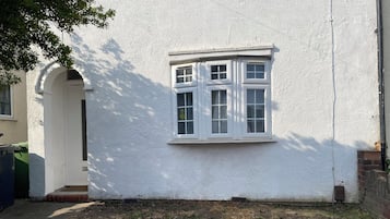Ein weißes Gebäude mit einem Fenster, einer Tür und einer Ziegelwand.