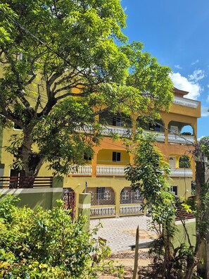 A multi-story building with balconies, surrounded by trees and greenery. - ABBY COURT (Mandeville)