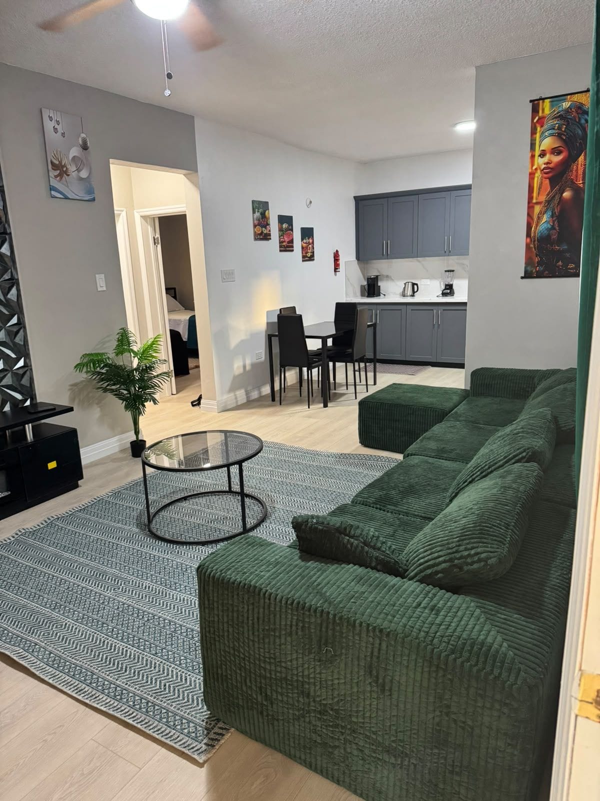 A modern living room with a green sofa, a glass coffee table, and a patterned rug.