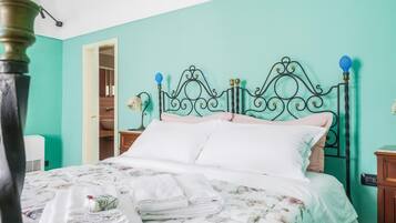 A bed with a floral bedspread, a nightstand with a lamp, and a teal-colored wall.