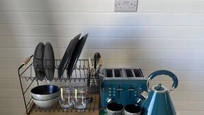 A wooden kitchen counter with a dish rack, a toaster, a kettle, and a set of mugs.
