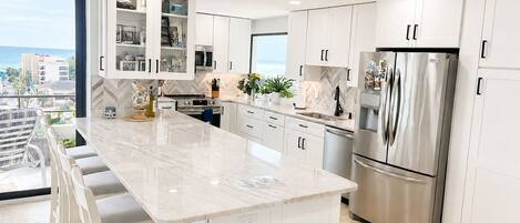 A modern kitchen with a large island, stainless steel appliances, and a view of the city.