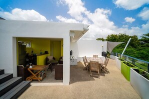 Eine moderne Außenpatio mit Essbereich, Grill und Küchenzeile inklusive Kühlschrank und Spüle.