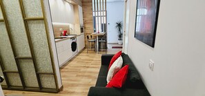 Eine moderne Küche mit Geschirrspüler, ein Essbereich mit Tisch und Stühlen sowie ein Wohnbereich mit Sofa und Kissen.