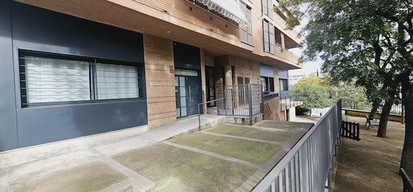 A modern building with a garage door, a staircase, and a small outdoor area with a bench.