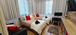 A hotel room with two beds, a TV, a desk, and a chair.