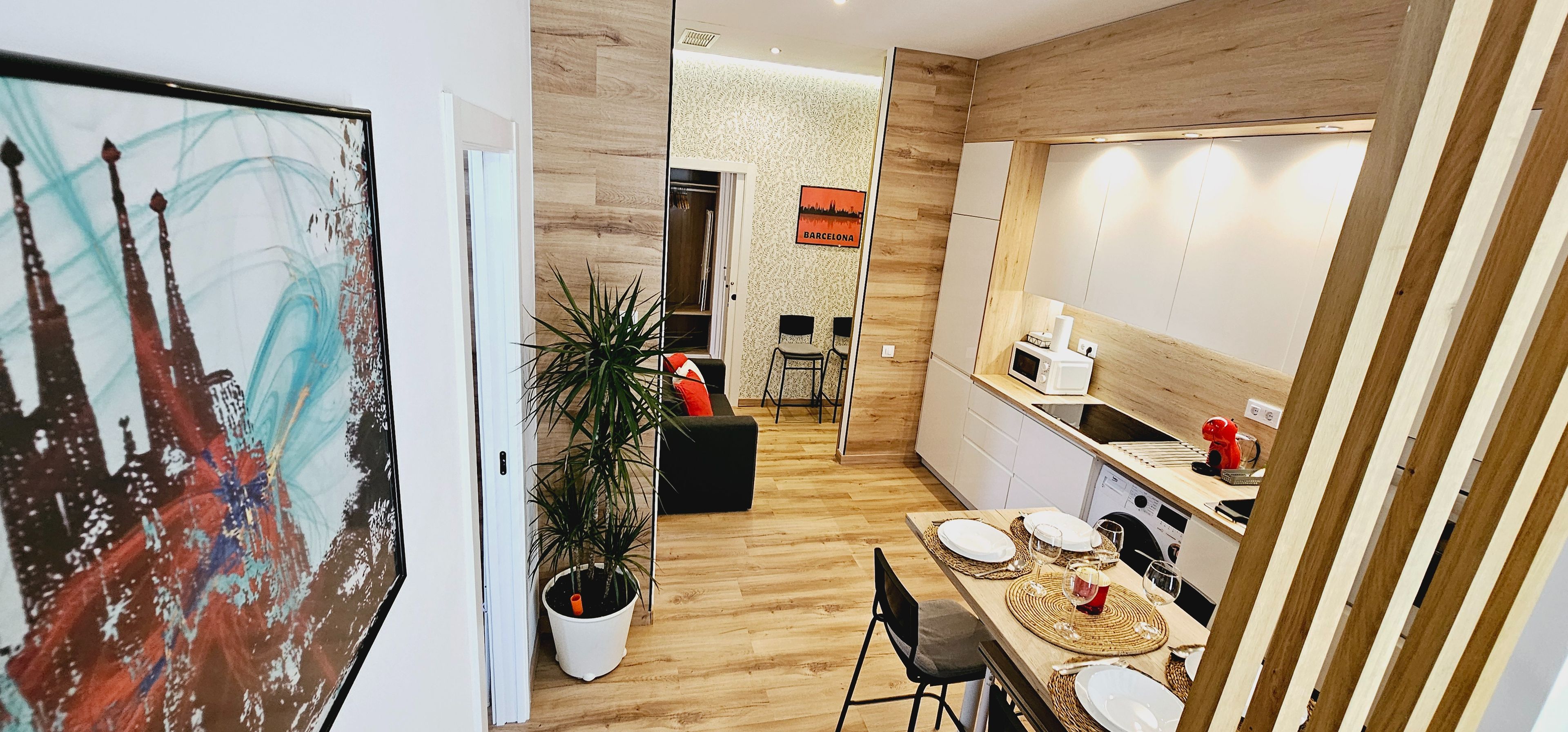 Eine moderne Küche mit Holzboden, einem Essbereich mit Tisch für zwei Personen und einer großen Kübelpflanze.