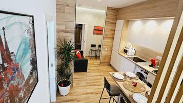 Eine moderne Küche mit Holzboden, einem Essbereich mit Tisch für zwei Personen und einer großen Kübelpflanze.