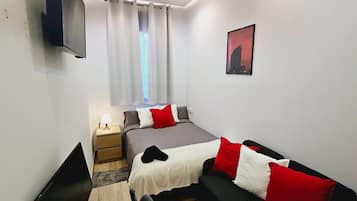 Ett sovrum med en säng, ett sängbord, en lampa och en tavla på väggen.