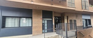 Ein mehrstöckiges Gebäude mit Backsteinfassade, großen Fenstern und einem Metallgeländer am Balkon.