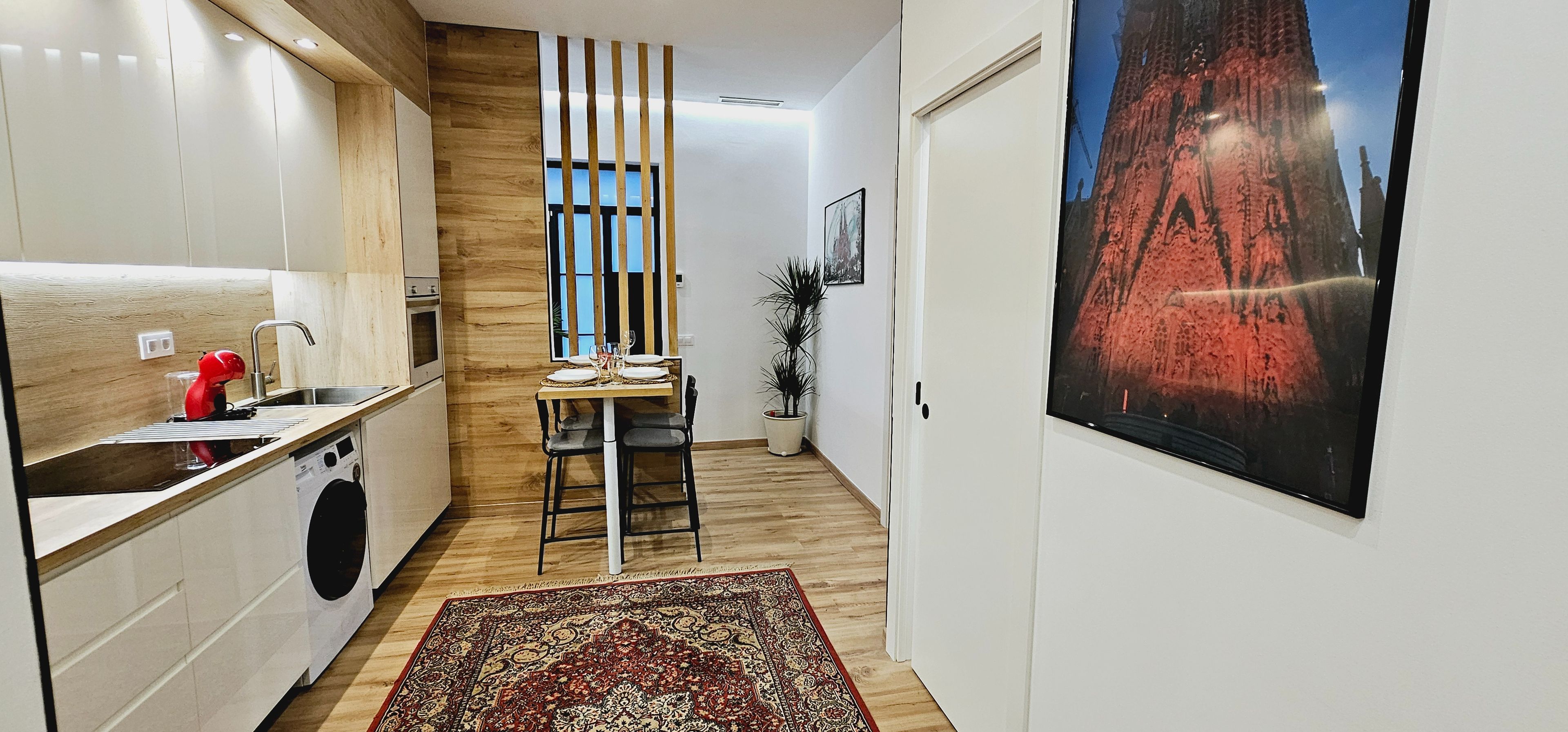 Ett modernt kök med trädetaljer, en matplats med en matta och en stor affisch med en stadsbild.