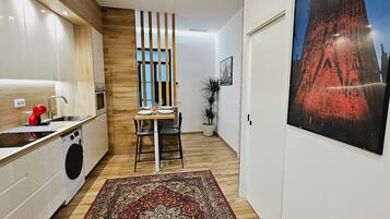 Ett modernt kök med trädetaljer, en matplats med en matta och en stor affisch med en stadsbild.