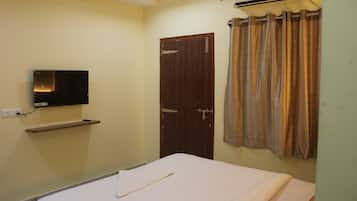 Una habitación con cama, televisión montada en la pared, una puerta y un aire acondicionado.