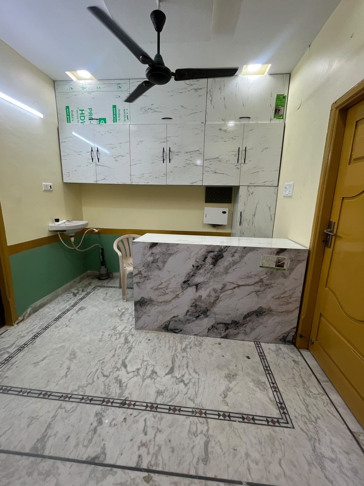 Una cocina con encimeras de mármol, ventilador de techo y pileta.