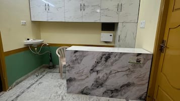Una cocina con encimeras de mármol, ventilador de techo y pileta.