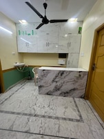 Una cocina con encimeras de mármol, ventilador de techo y pileta.