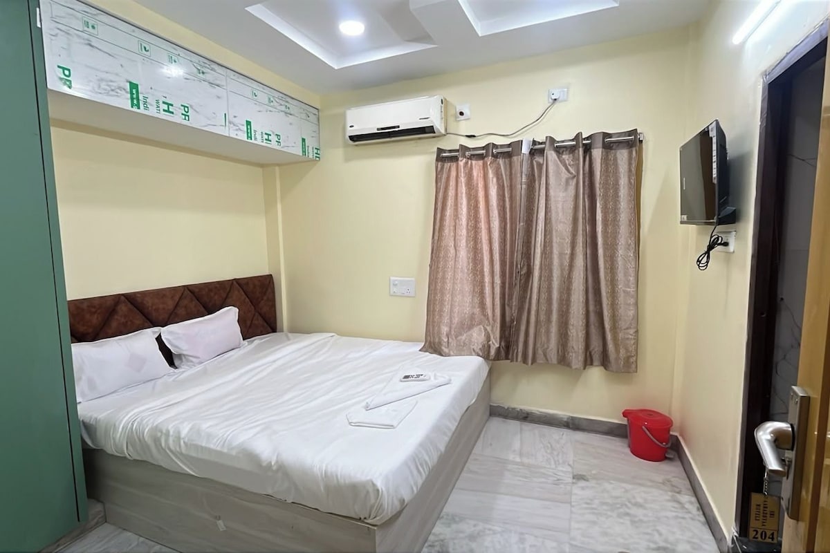 Une chambre d’hôtel équipée d’un lit, d’un climatiseur, d’une télévision et de rideaux.