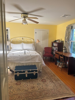 A bedroom with a bed, a desk, a chair, a wardrobe, and a suitcase.