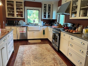 A kitchen with white cabinets, a stainless steel stove, and a large window.