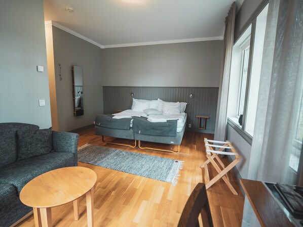 A modern bedroom with a bed, a sofa, a small table, and a window.