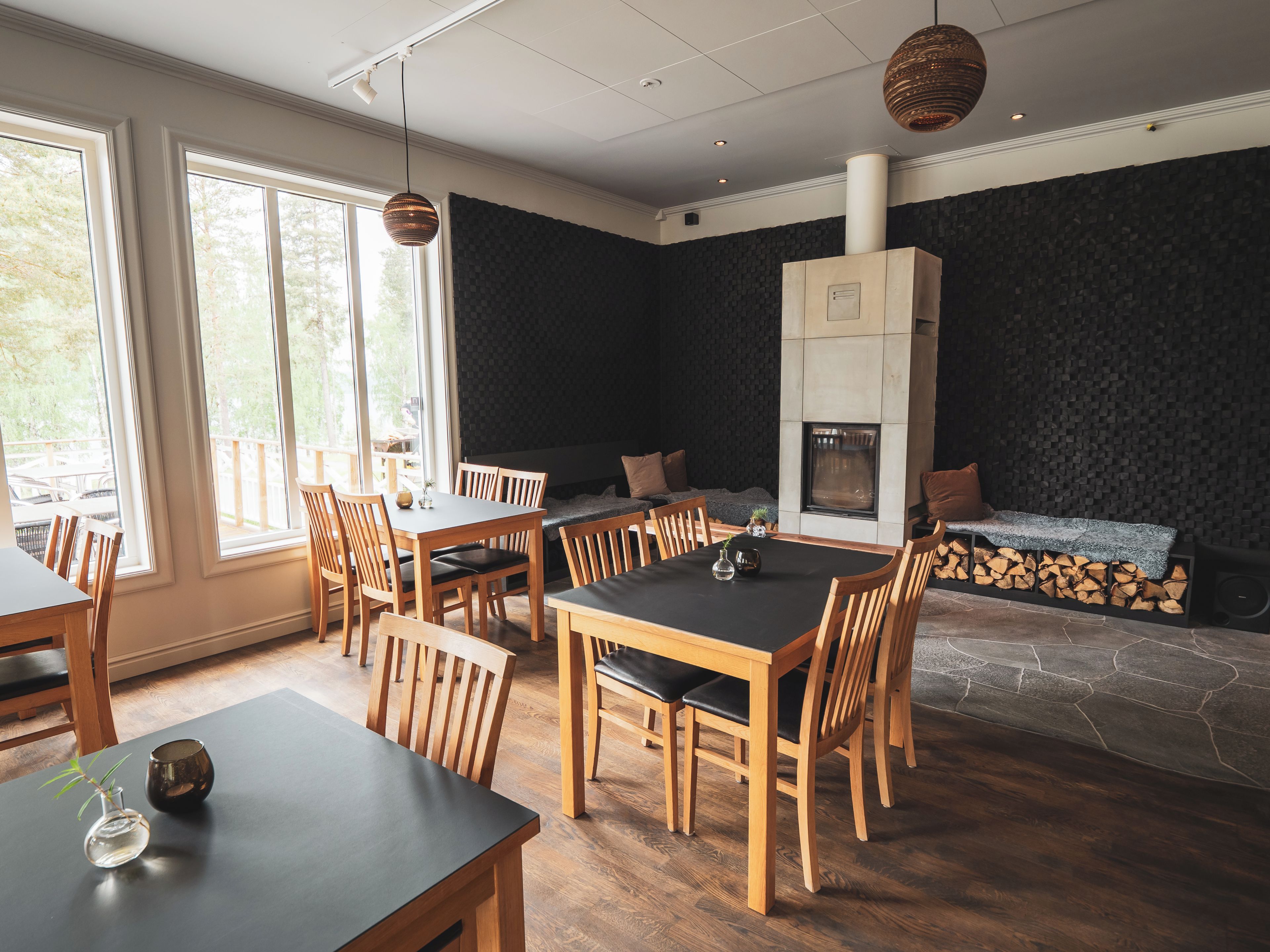 A dining area with a large table and chairs, a fireplace, and a view of the outdoors.
