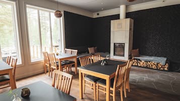 A dining area with a large table and chairs, a fireplace, and a view of the outdoors.