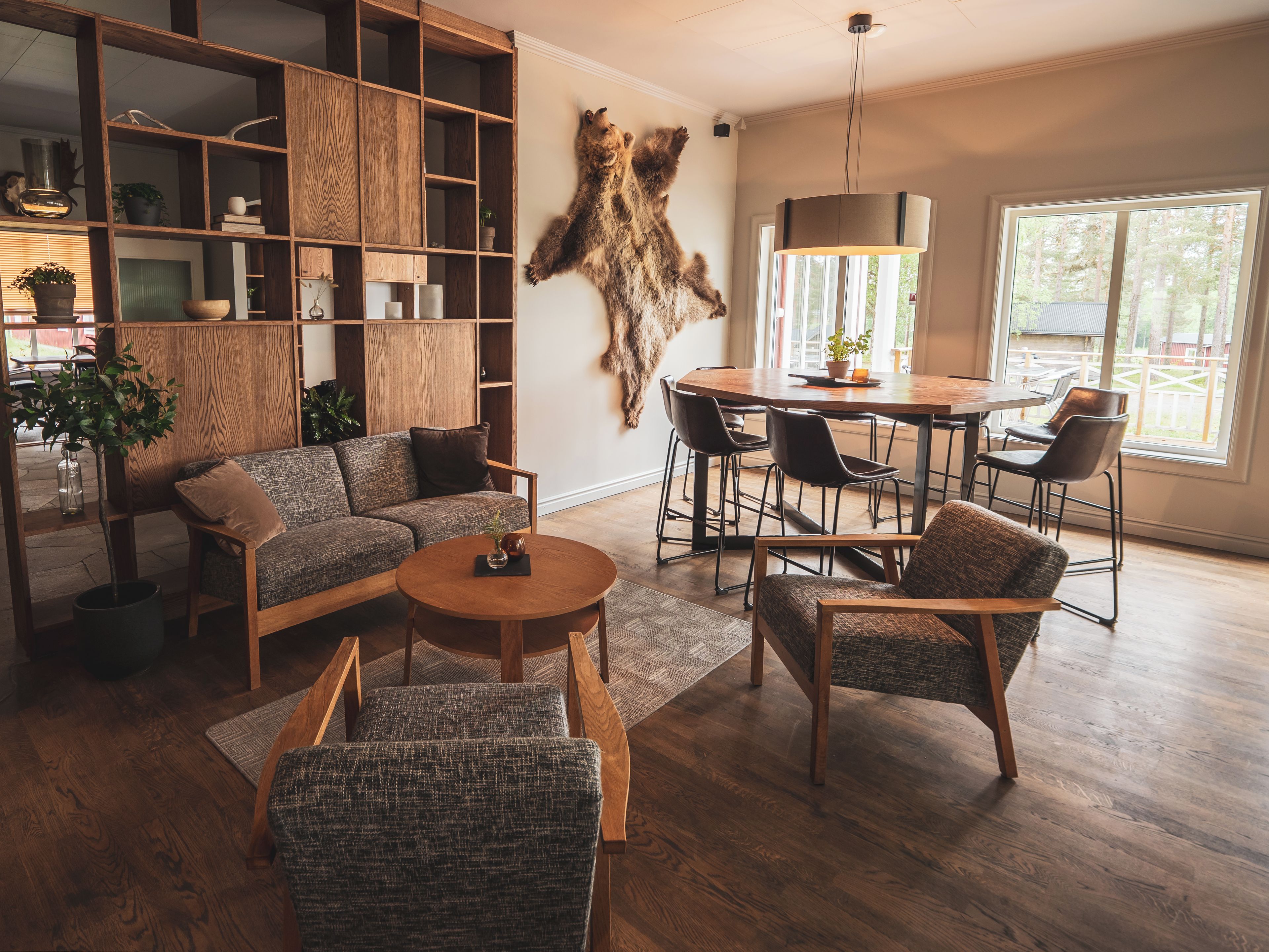 A modern living room with a wooden sofa, a round coffee table, and a dining area with chairs and a table.
