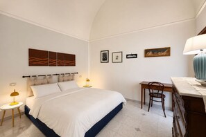 Ein Hotelzimmer mit Bett, Nachttischen, Schreibtisch und Stuhl.