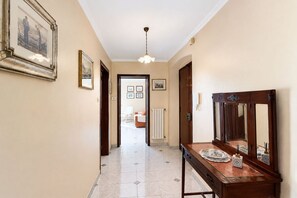 A hallway with a wooden bench, a mirror, and framed pictures on the walls. - GuestHost - Central Apartment near train station (Trani)