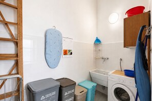 Casa de banho com máquina de lavar roupa, um calendário e lixeiras.